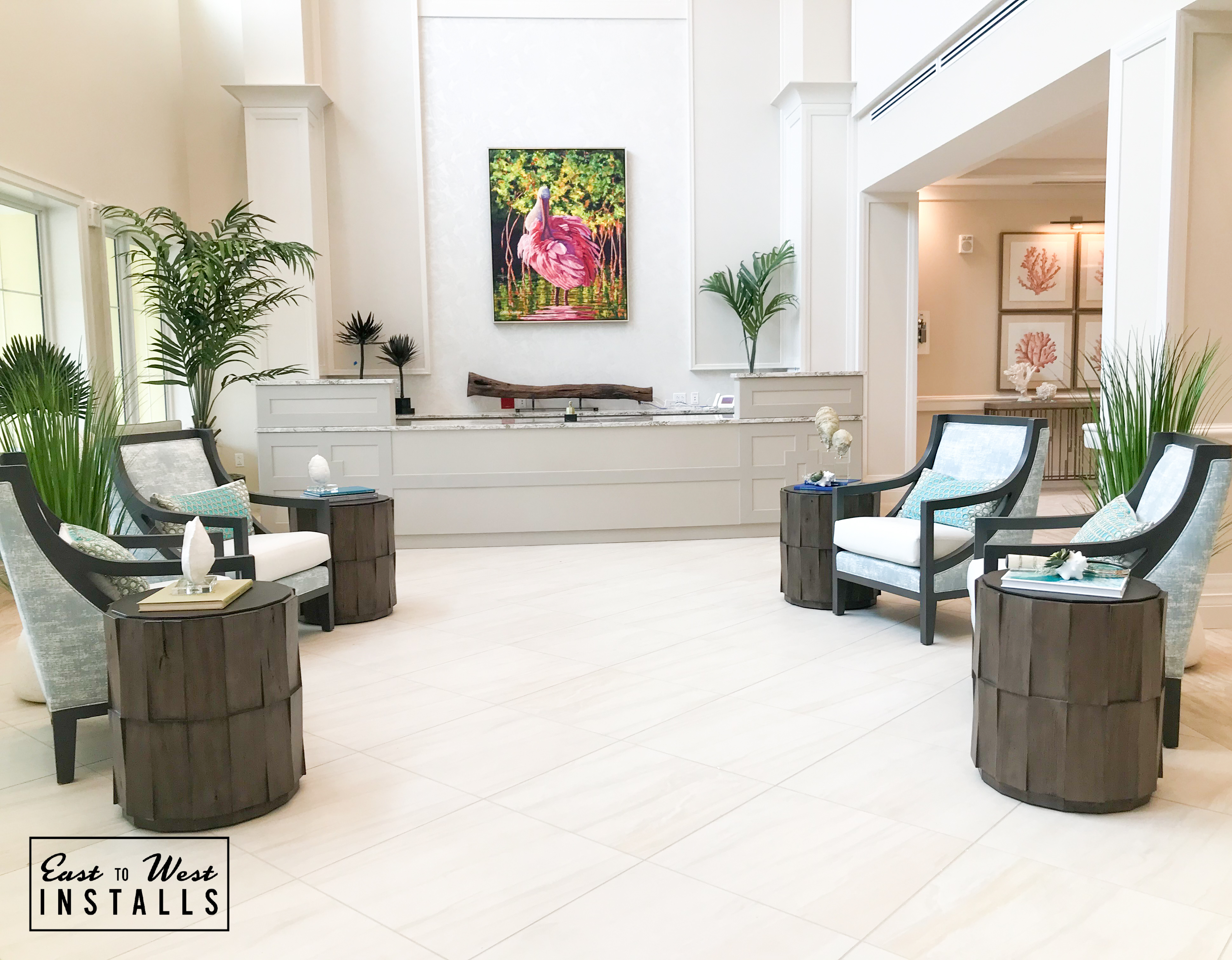 Bright atrium lobby with coastal artwork and teal accent chairs