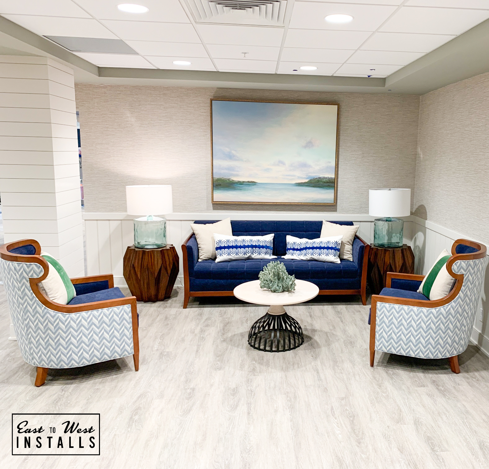 Coastal lounge with navy sofa, chevron chairs, seascape artwork