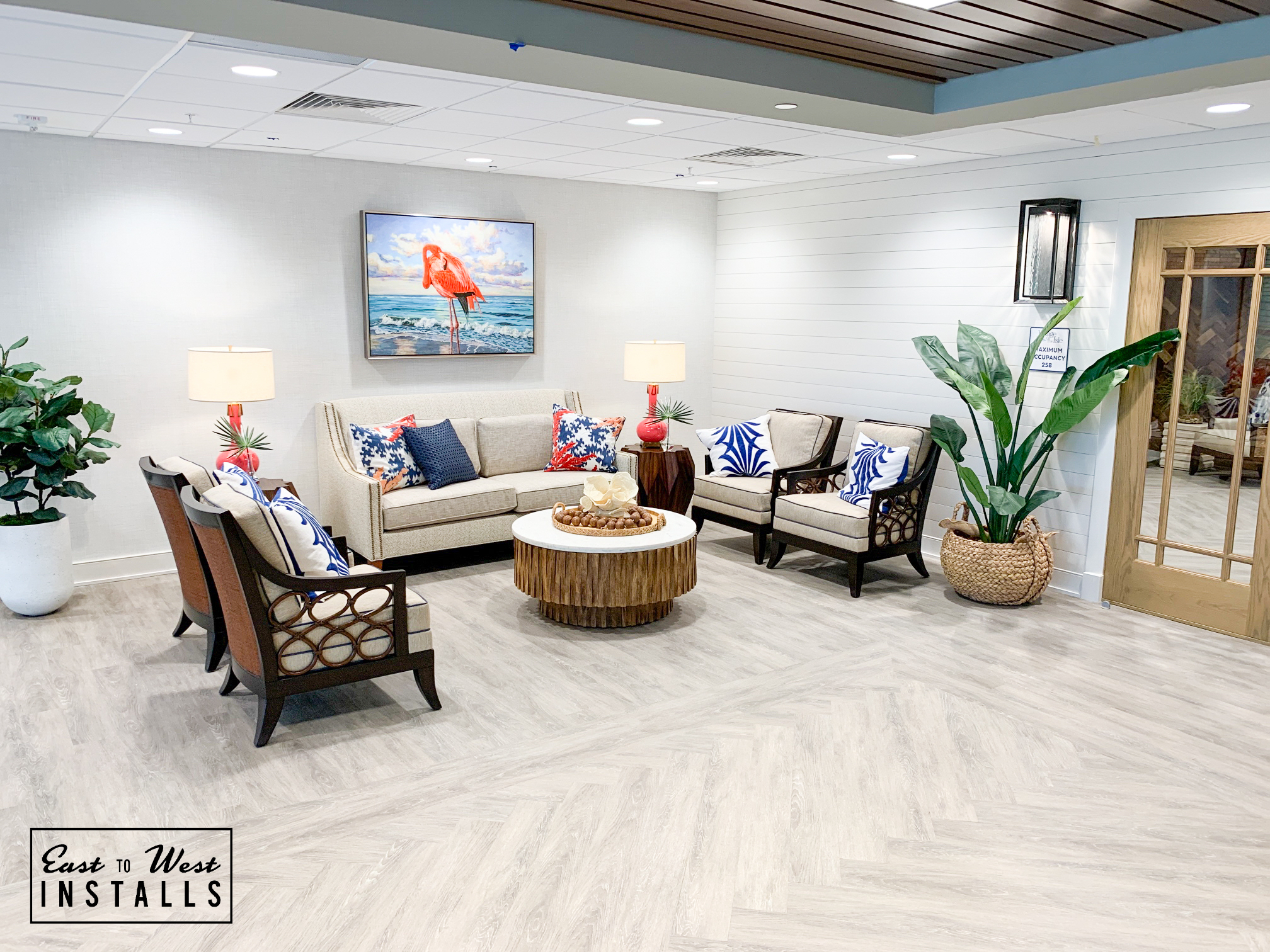Coastal lounge with shiplap wall, linen sofa, and tropical artwork