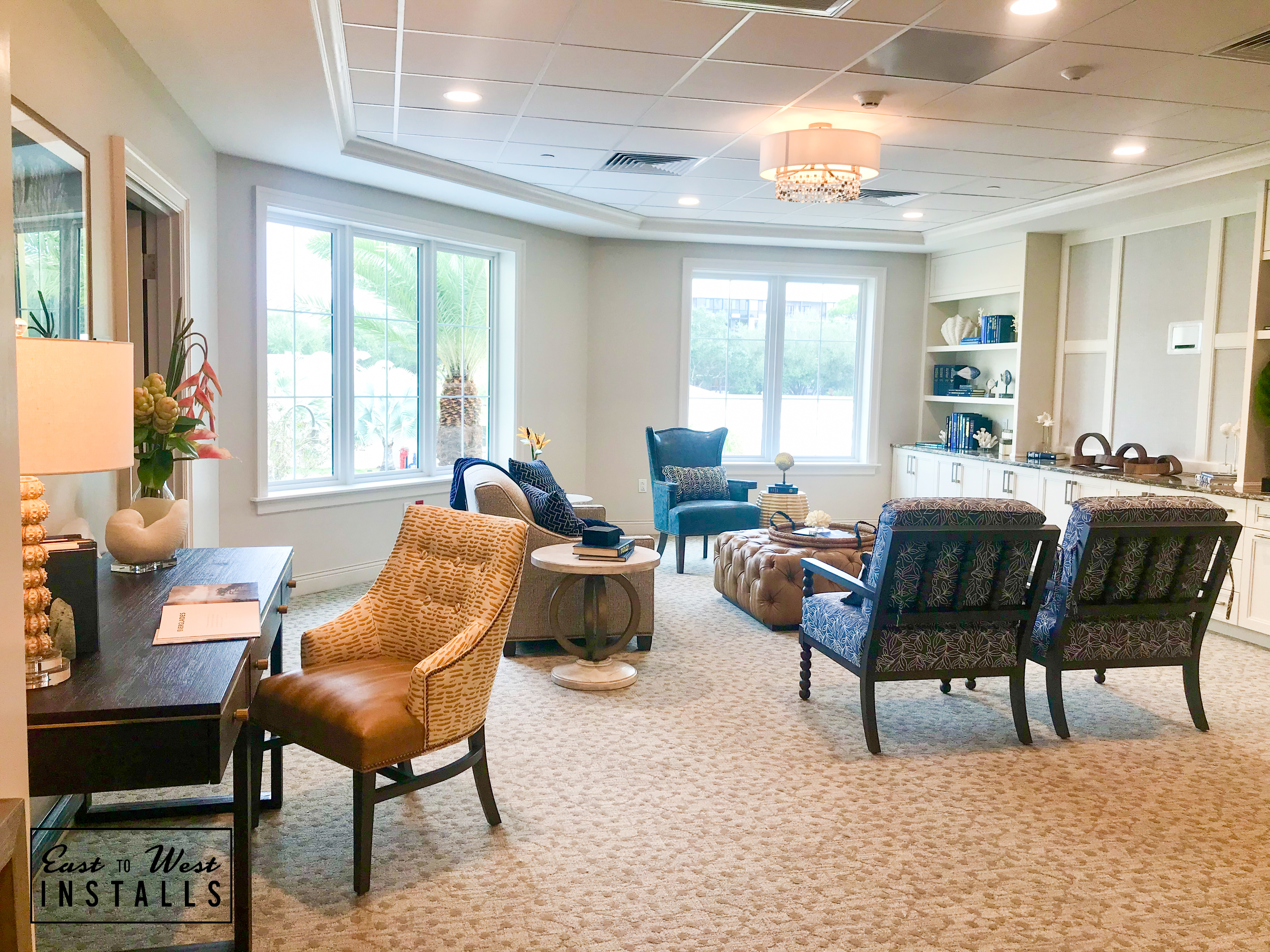 Resident lounge with palm tree views, layered seating and built-in bookshelves